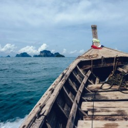 Brown Wooden Boat on Sea Overlooking Rocky Island